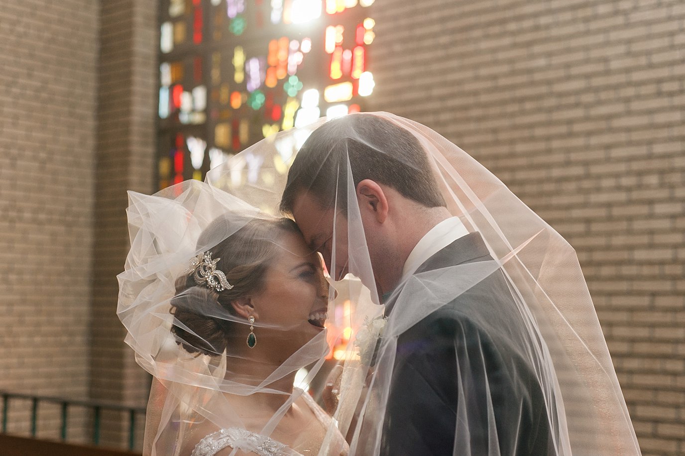 bride and groom smiling near stain glass windows