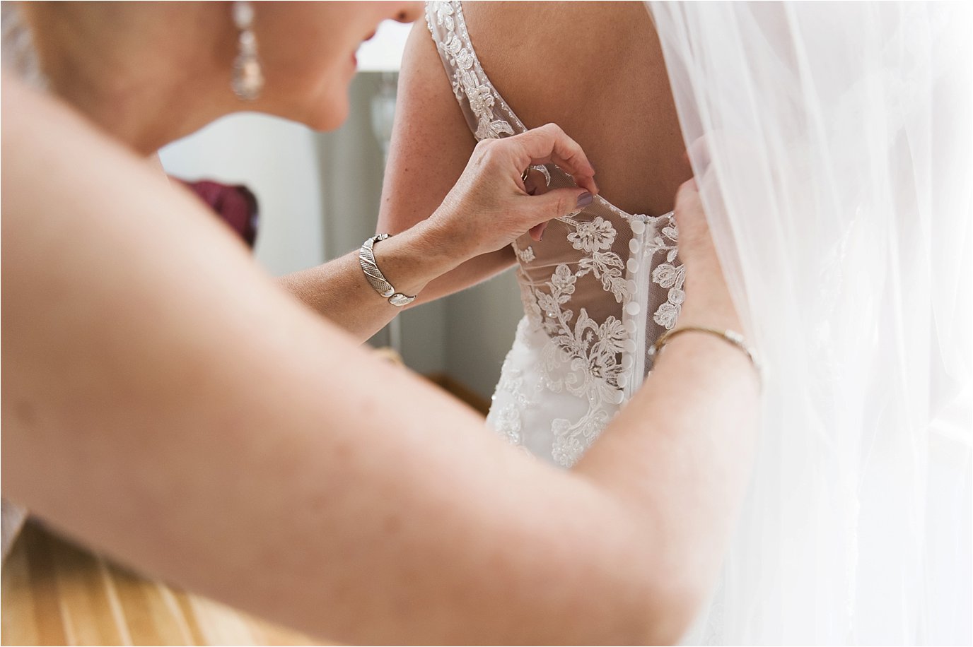 Mother helping bride get dressed